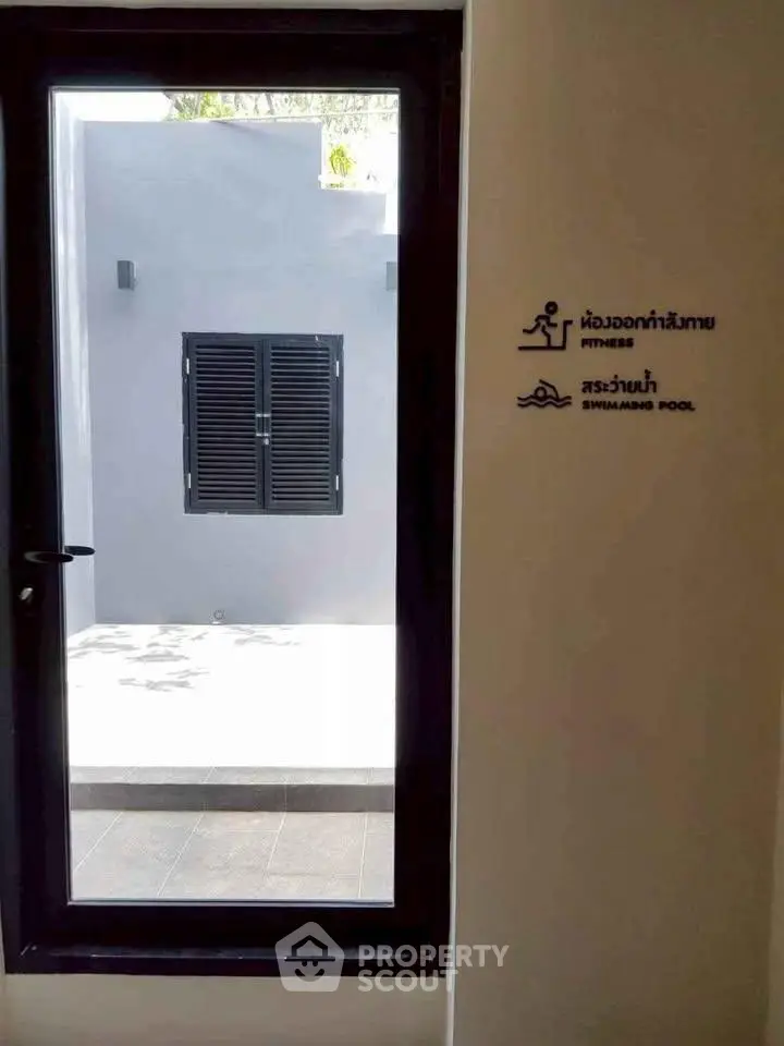 Modern building entrance with fitness and swimming pool signs, sleek design.