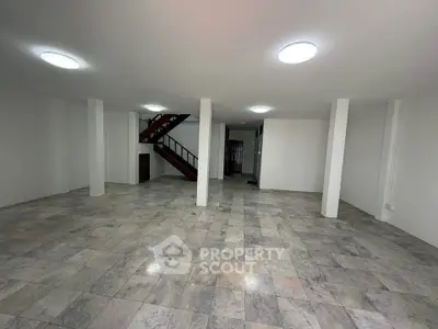 Spacious open-plan interior with tiled flooring and staircase, ideal for versatile use.