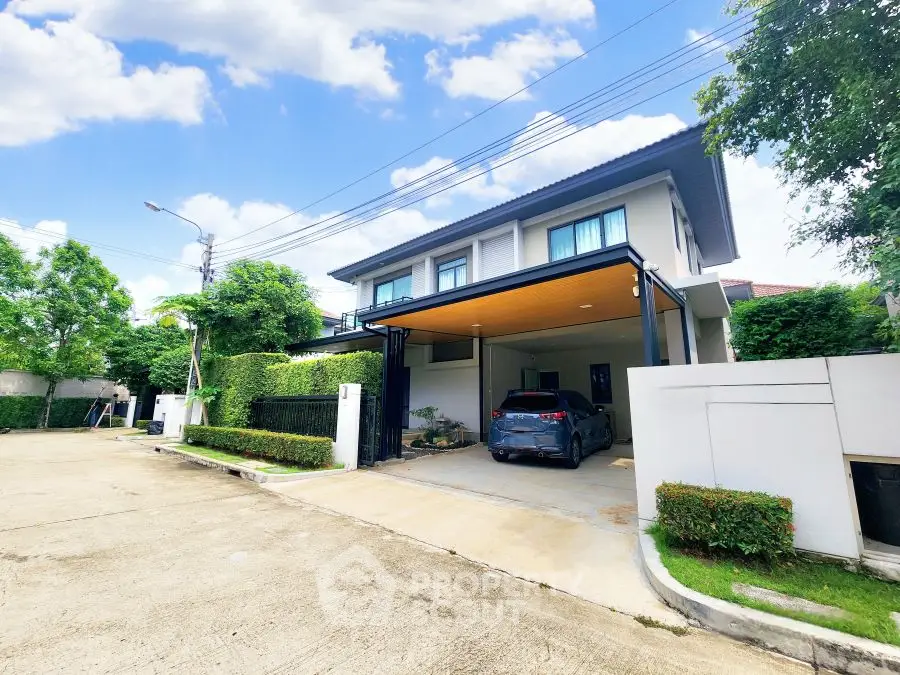 Modern two-story house with carport and lush greenery in a serene neighborhood.
