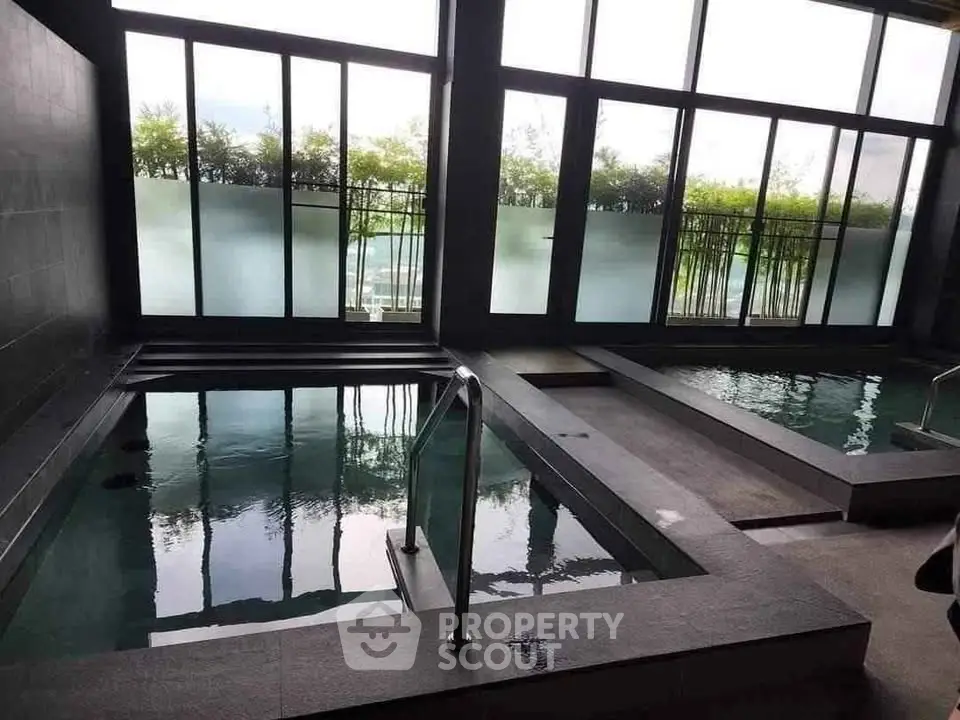 Luxurious indoor pool area with modern design and large windows offering natural light.