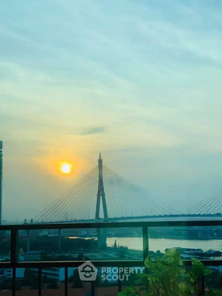 Stunning sunset view from a balcony overlooking a river and bridge, perfect for serene evenings.