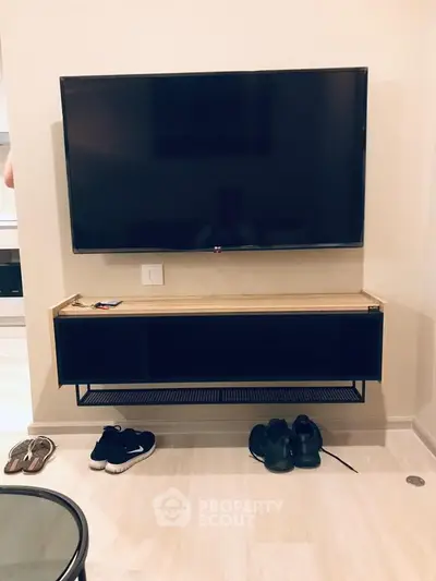 Modern living room with wall-mounted TV and sleek storage unit, showcasing minimalist design and functionality.