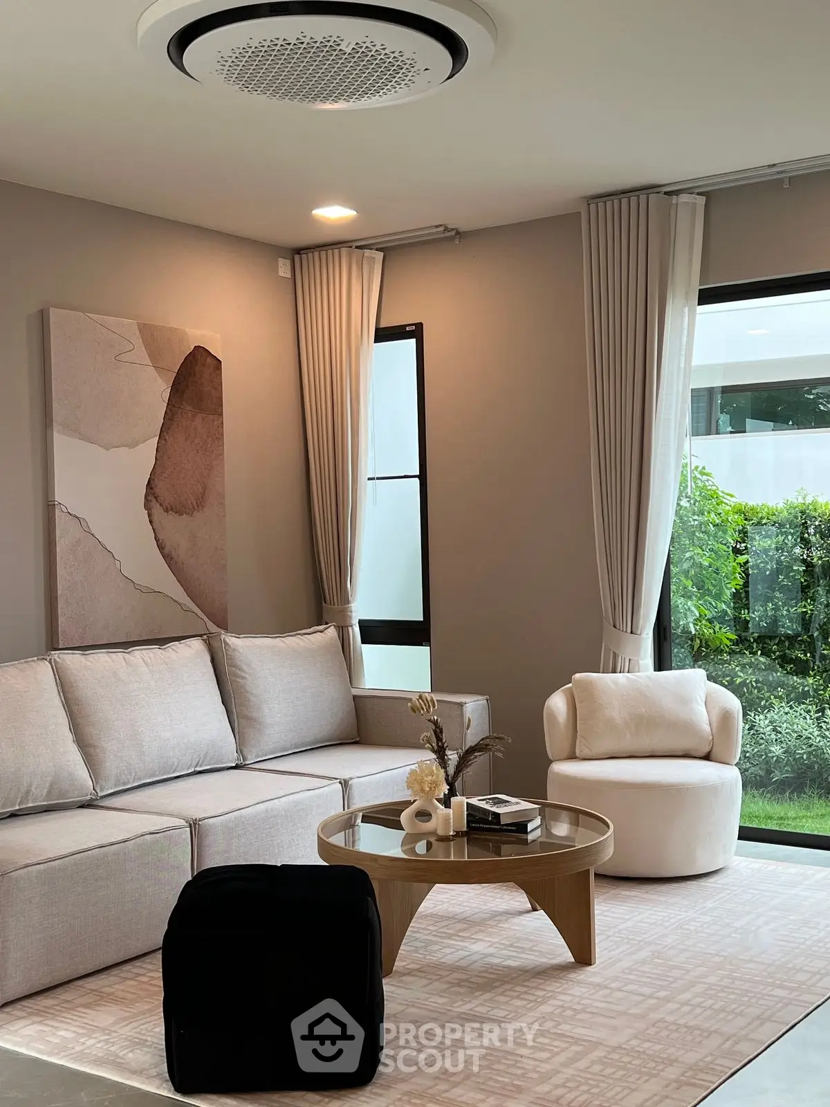 Elegant living room with modern furniture and large windows overlooking lush greenery.