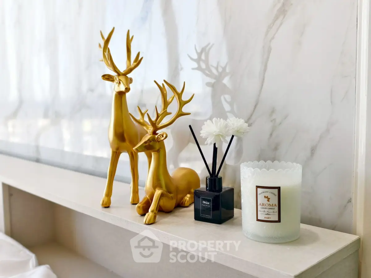 Elegant shelf decor with golden deer figurines and scented candle in modern interior.