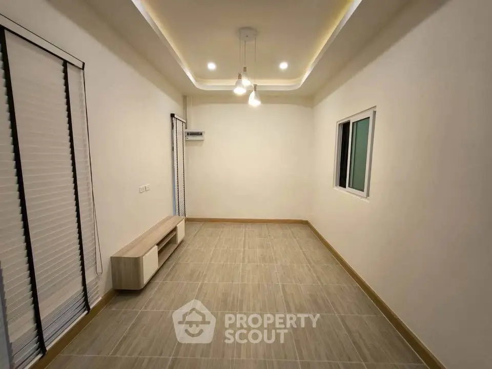 Spacious empty room with modern lighting and tiled flooring, perfect for customization.