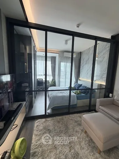 Modern studio apartment with glass partition, cozy living area, and stylish bedroom.