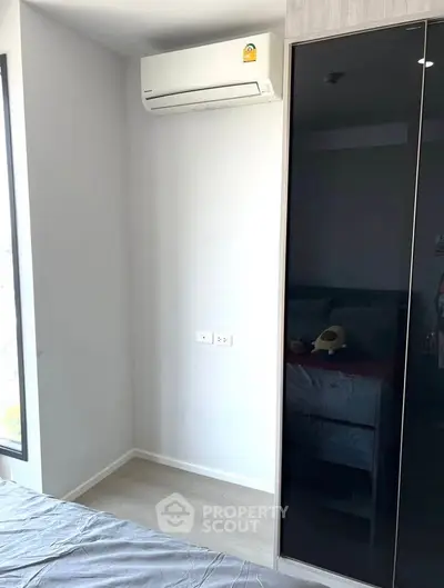 Modern bedroom with sleek black wardrobe and air conditioning unit, perfect for urban living.
