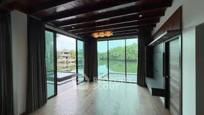 Stunning living room with large windows offering serene lake views and modern wooden ceiling design.