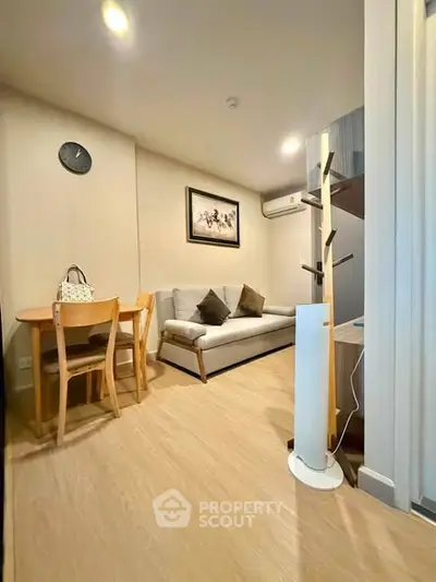 Cozy living room with modern decor and wooden flooring, featuring a comfortable sofa and dining area.