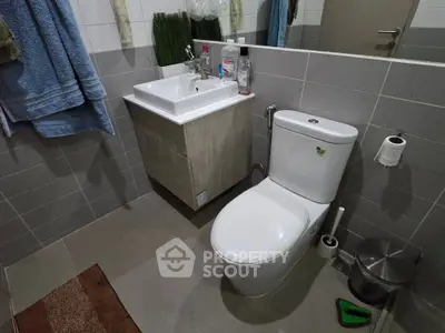 Modern bathroom with sleek fixtures and neutral tiles, featuring a compact sink and toilet setup.