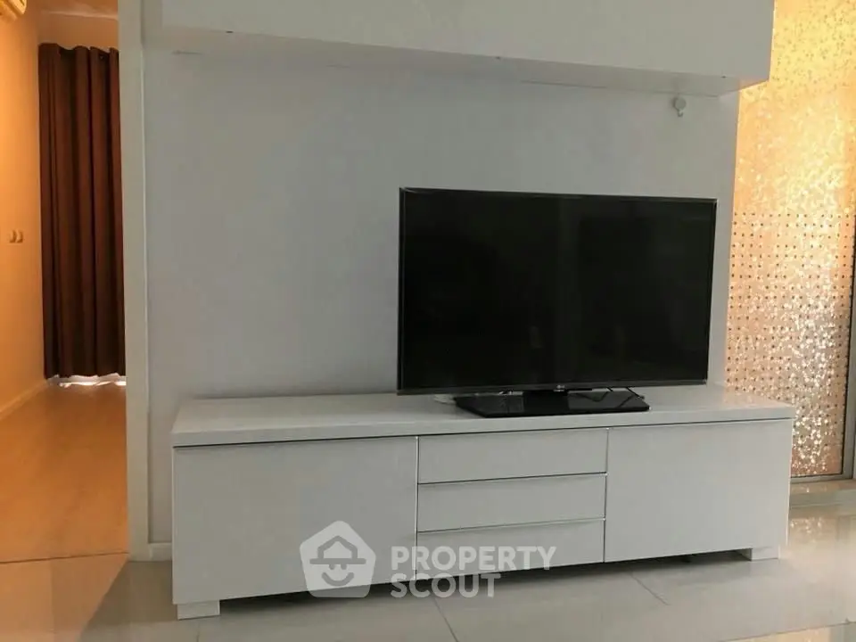 Modern living room with sleek white TV stand and flat-screen television.