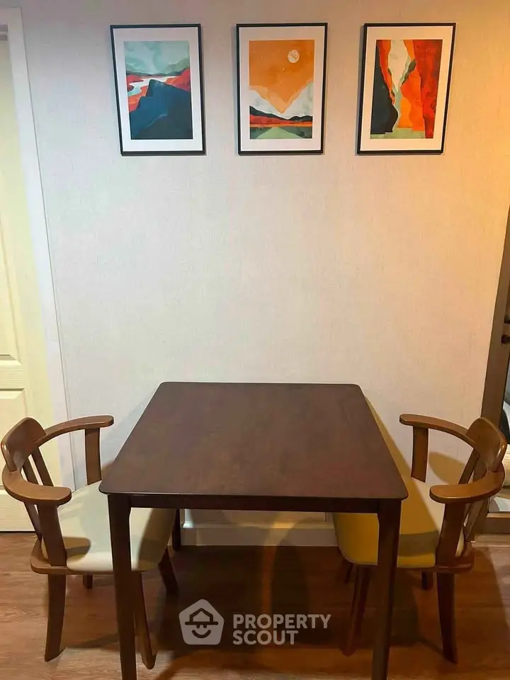 Cozy dining area with wooden table and chairs, complemented by modern art on the wall.