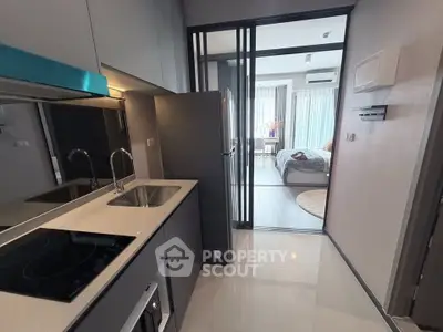 Modern apartment kitchen with sleek design and view into cozy bedroom