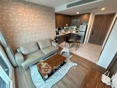 Modern living room with open kitchen, stylish decor, and cozy seating area in a contemporary apartment.