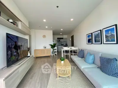 Modern living room with stylish decor and open layout, featuring a cozy sofa and large TV.