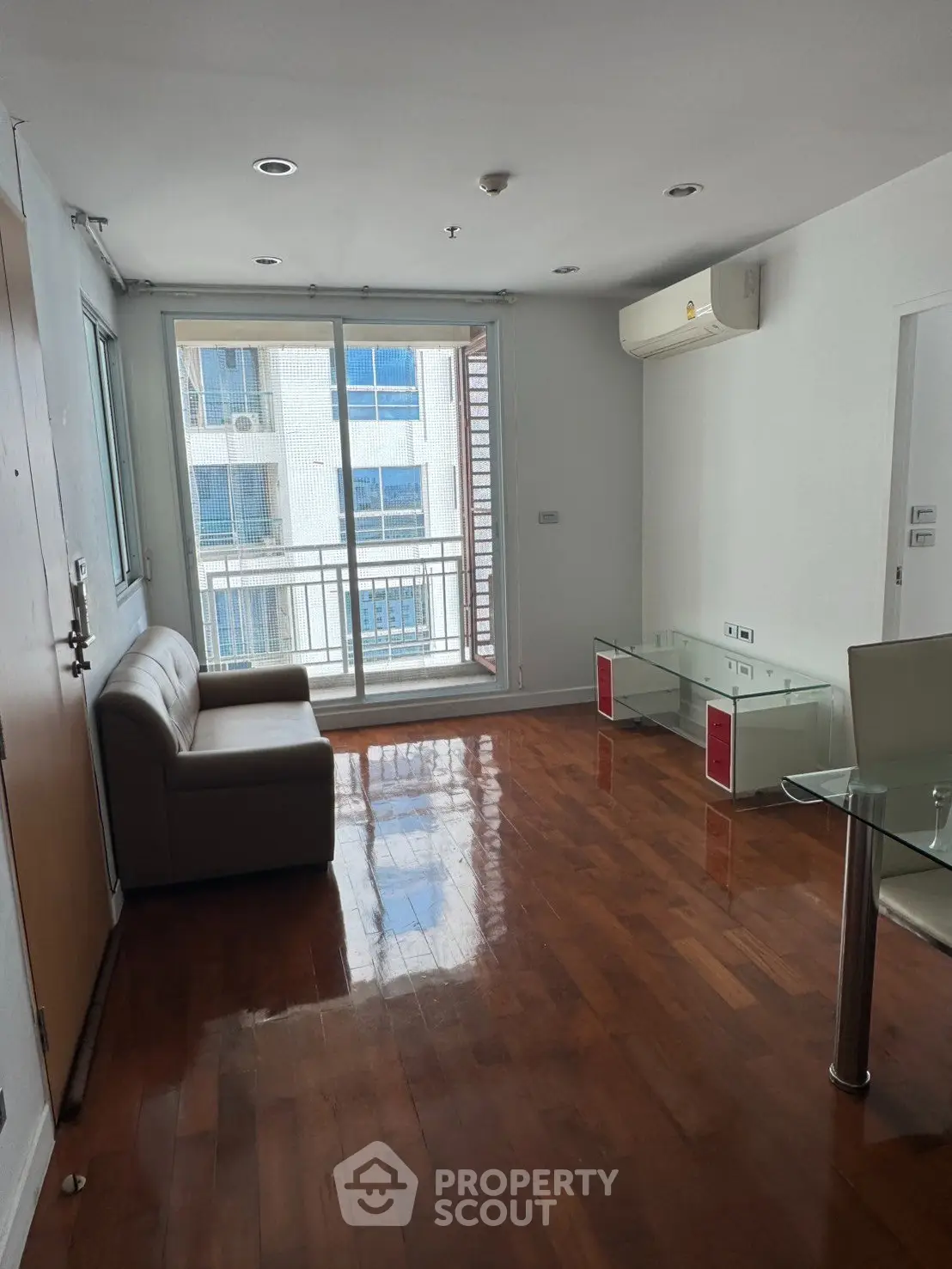 Spacious living room with wooden flooring and balcony view in modern apartment.