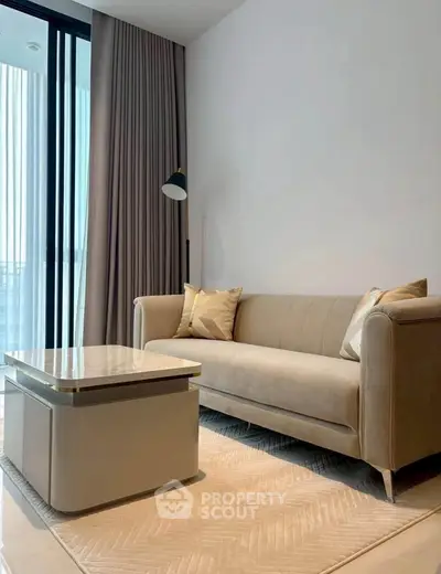 Modern living room with elegant beige sofa and stylish coffee table near large window.