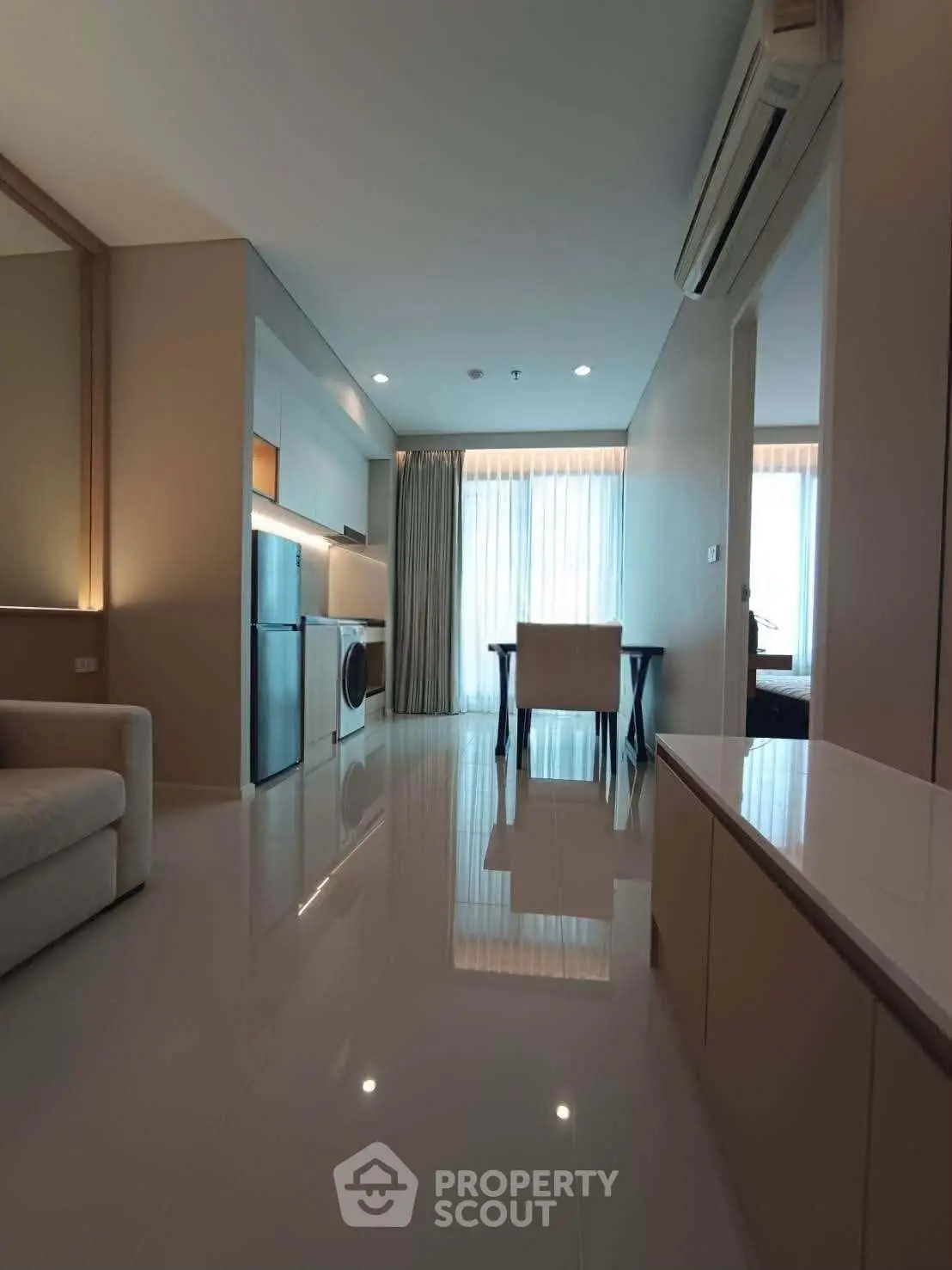Modern apartment interior with sleek design, featuring open layout, washing machine, and dining area.