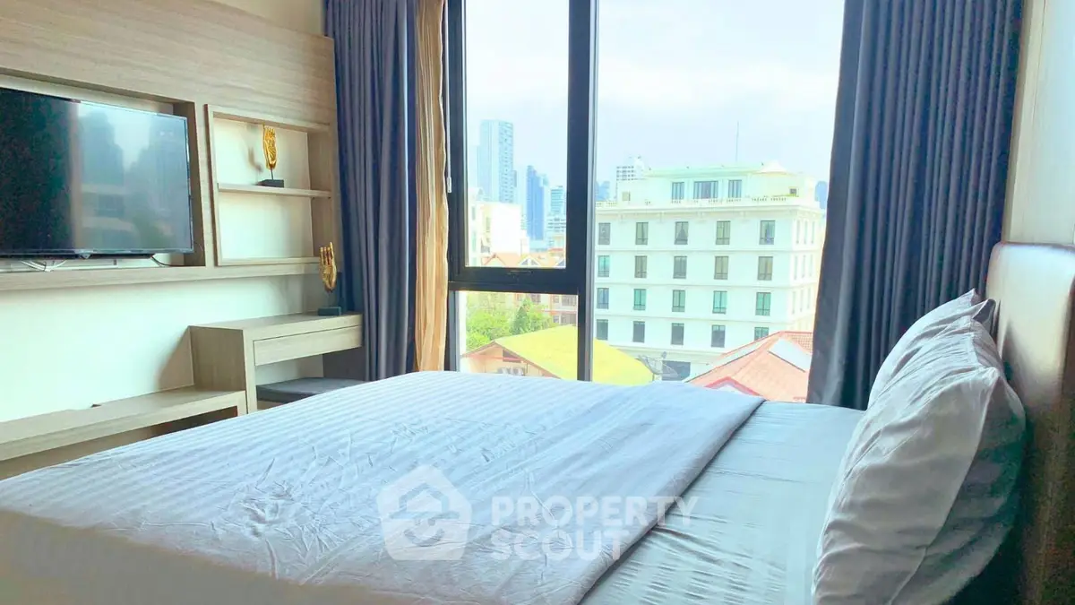 Spacious bedroom with city view and modern furnishings in urban apartment.