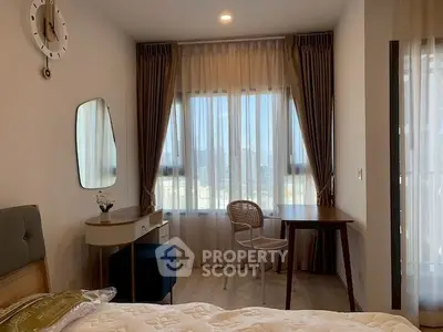 Cozy bedroom with stylish furniture and large window offering natural light.