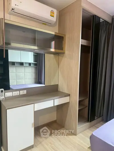 Modern bedroom with built-in wardrobe and air conditioning unit, featuring sleek design and ample storage space.