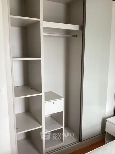 Spacious modern wardrobe with shelves and hanging rod in a stylish bedroom.