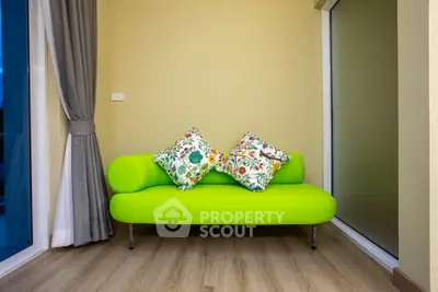 Stylish small living room with vibrant green sofa and floral cushions.