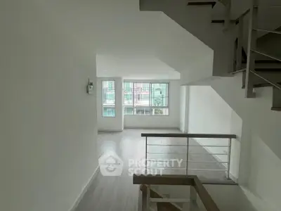 Spacious modern interior with large windows and sleek staircase, perfect for urban living.