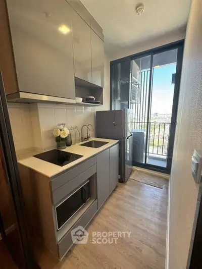 Modern compact kitchen with sleek cabinetry and balcony view, perfect for urban living.