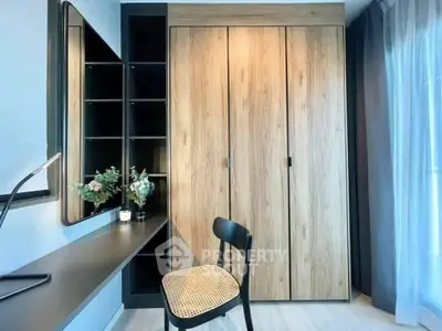 Modern study area with sleek desk, chair, and wooden wardrobe in bright room.
