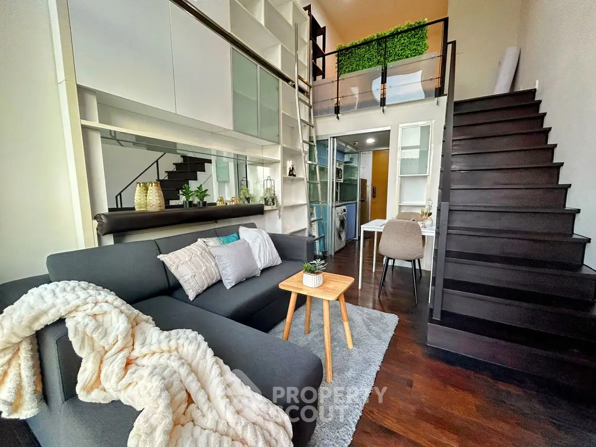 Modern loft-style living room with mezzanine, sleek staircase, and cozy decor.