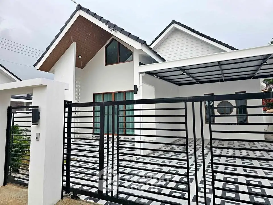 Modern white house with stylish gate and carport, featuring geometric driveway design.