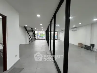 Spacious modern commercial space with glass partitions and staircase, ideal for businesses.