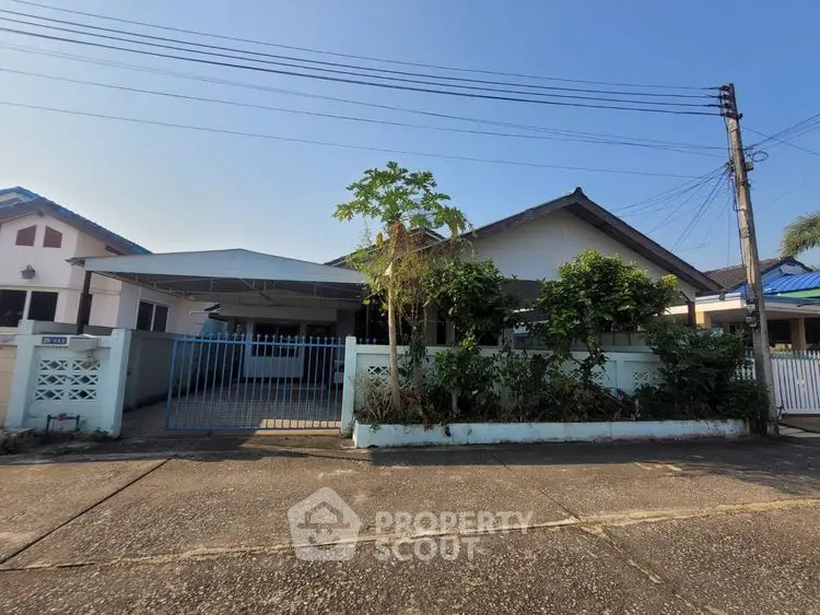 Charming single-story home with gated entrance and lush greenery in a peaceful neighborhood.
