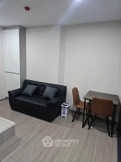 Modern living room with sleek black sofa and stylish dining set in a cozy apartment.