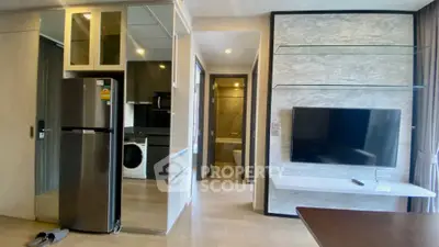 Modern apartment interior with sleek kitchen and living area, featuring a wall-mounted TV and stylish decor.
