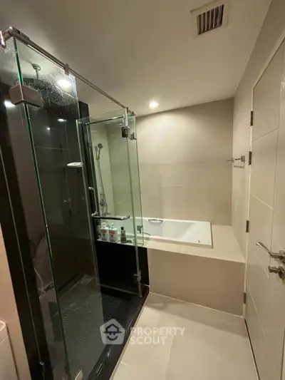 Modern bathroom with glass shower and built-in bathtub in sleek design.