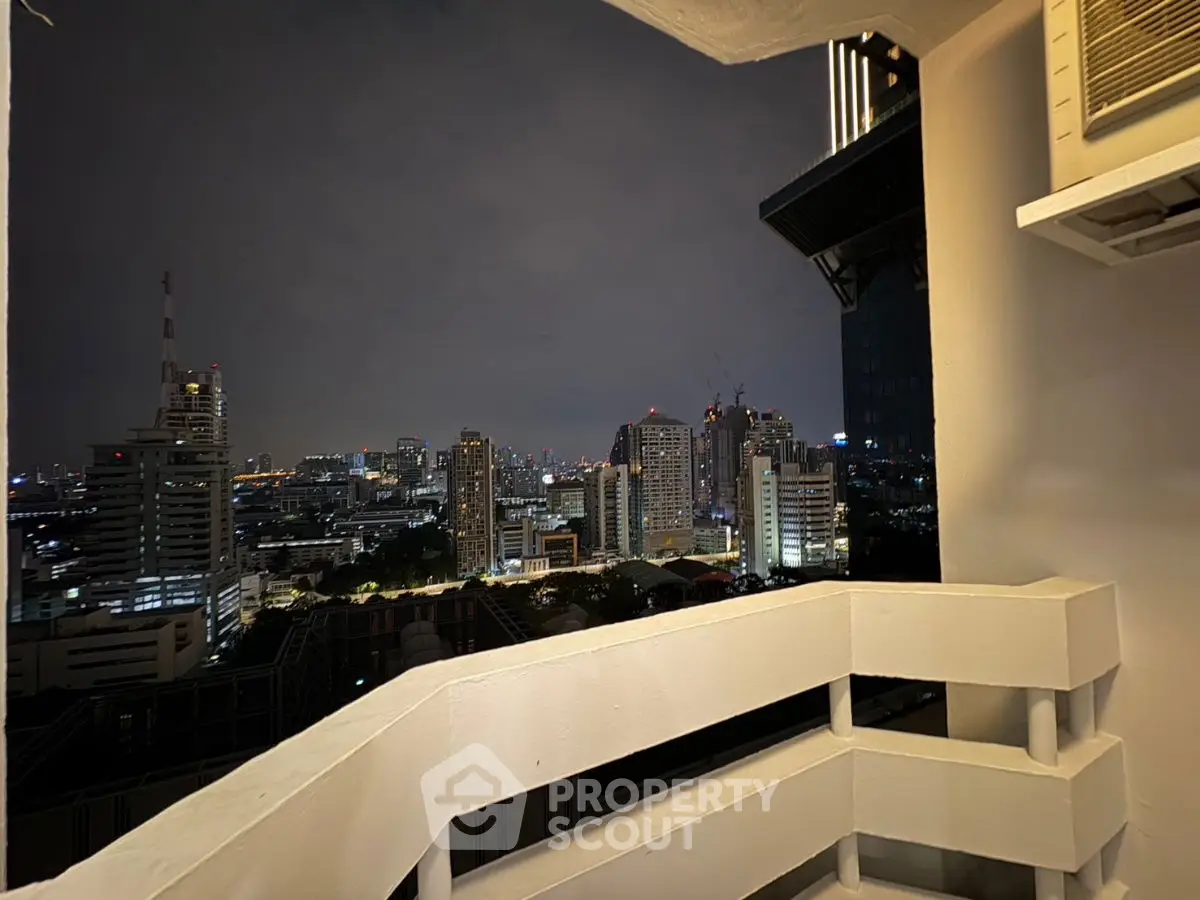Stunning cityscape view from a high-rise balcony at night, showcasing urban skyline and vibrant lights.