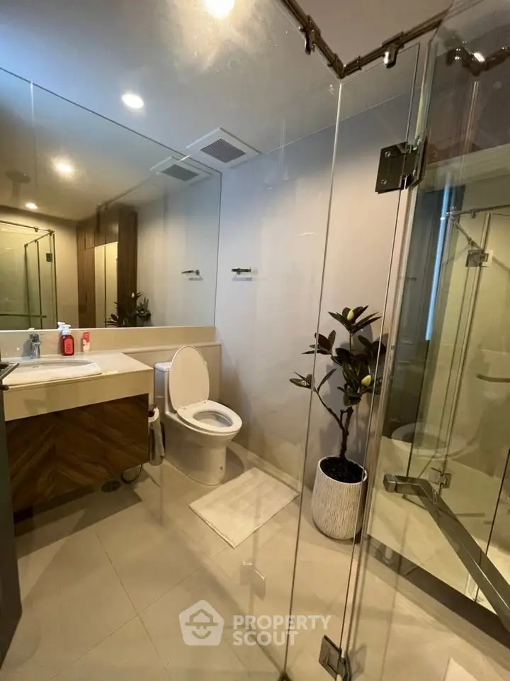 Modern bathroom with glass shower, sleek vanity, and elegant decor in a contemporary home.