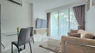 Modern living room with large TV, cozy sofa, and dining area near floor-to-ceiling windows.