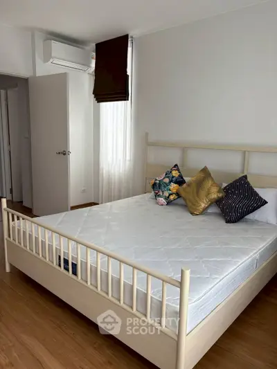 Modern bedroom with stylish decor and natural light, featuring a comfortable bed and wooden flooring.