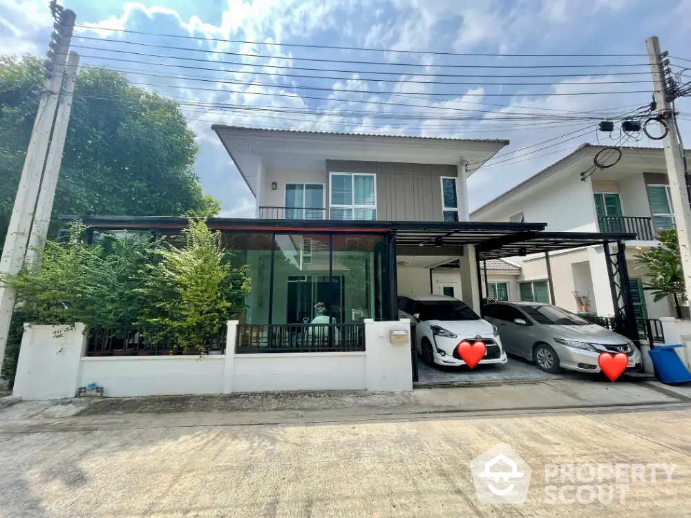 Modern two-story house with carport and lush greenery in a serene neighborhood.