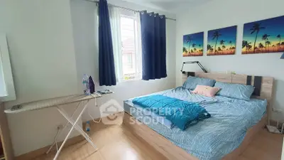 Cozy bedroom with modern decor and natural light, featuring a comfortable bed and stylish artwork.
