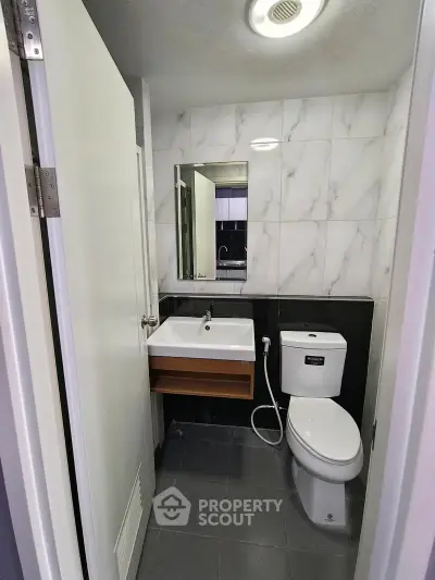 Modern bathroom with sleek design, featuring a wall-mounted sink and contemporary toilet.
