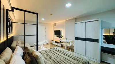 Modern bedroom with stylish decor and ample natural light, featuring a cozy bed and sleek furniture.