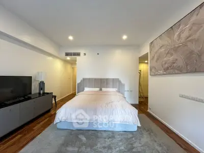Spacious modern bedroom with elegant decor and cozy ambiance, featuring a plush bed and stylish furniture.