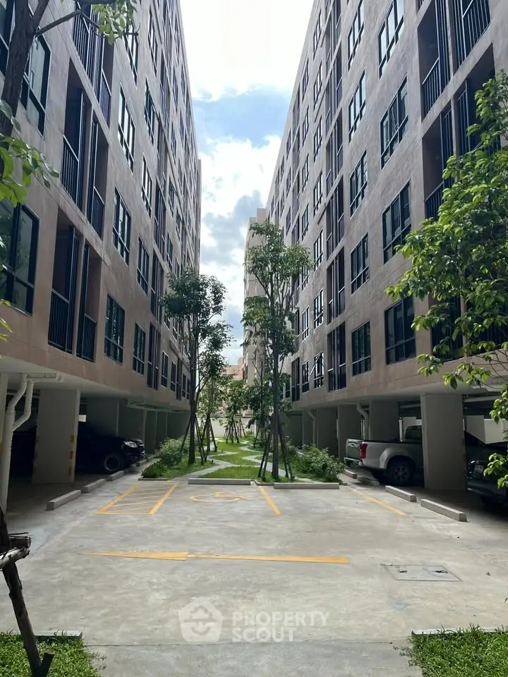 Modern apartment complex with spacious parking and lush greenery