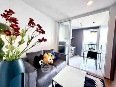 Modern living room with plush sofa and open kitchen leading to a balcony with city view.