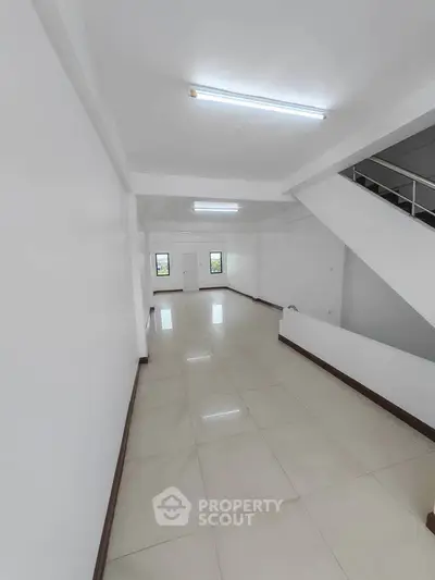 Spacious open-plan interior with modern staircase and bright lighting, ideal for versatile living or office space.