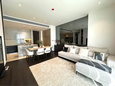 Luxurious open-plan living room with modern kitchen and elegant dining area, featuring plush sofa and stylish decor.